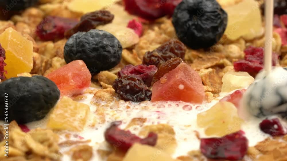 Pouring fresh milk into ceramic bowl of organic crunchy cereals breakfast with dried preserved tropical fruit. Pouring fresh milk into ceramic bowl of organic crunchy cereals breakfast with dried preserved tropical fruit.