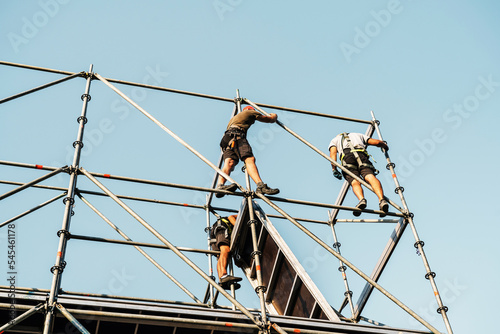 Builders mount a concert stage. Workers build a metal structure to install a mobile platform. Preparation for mass events and entertainment shows. unrecognizable person