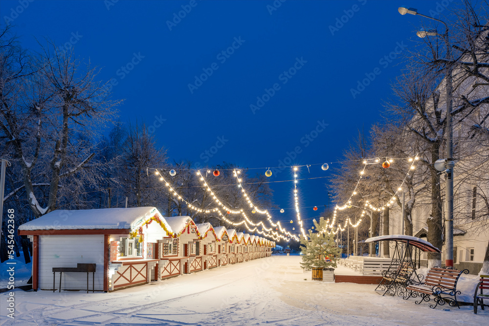 New Year's wooden houses decorated with garlands and tinsel on an early snowy frosty morning.