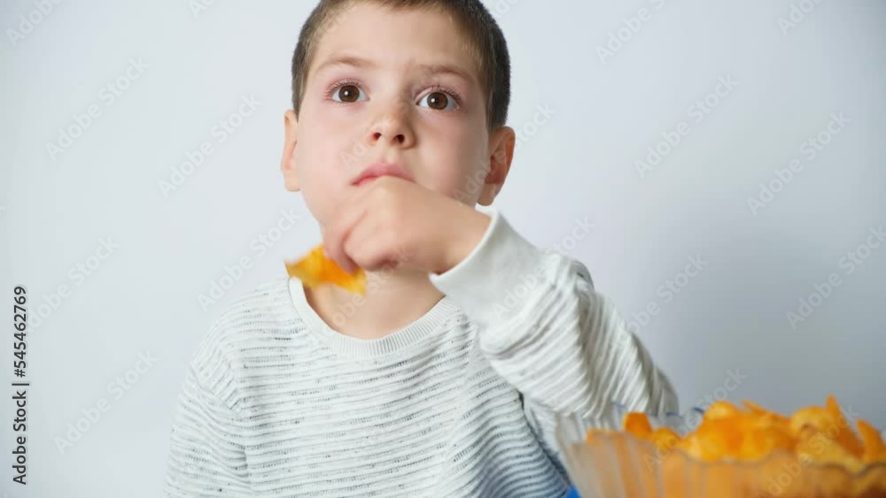 Cute preschool boy eats potato chips, unhealthy food for kids Cute preschool boy eats potato chips, unhealthy food for kids