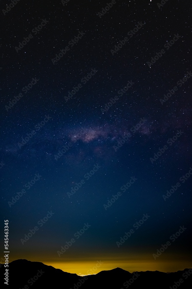 Vertical shot of the beautiful starry sky and the Milky Way over the silhouettes of mountains Vertical shot of the beautiful starry sky and the Milky Way over the silhouettes of mountains