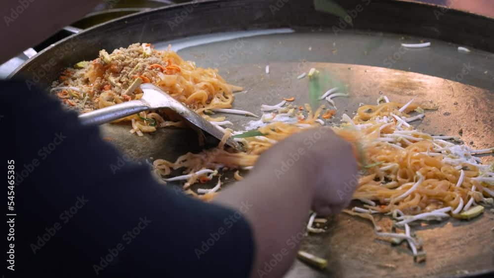 Pad Thai Bangkok Street food being cook on a flat Thai Wok with another order being ready on the side.