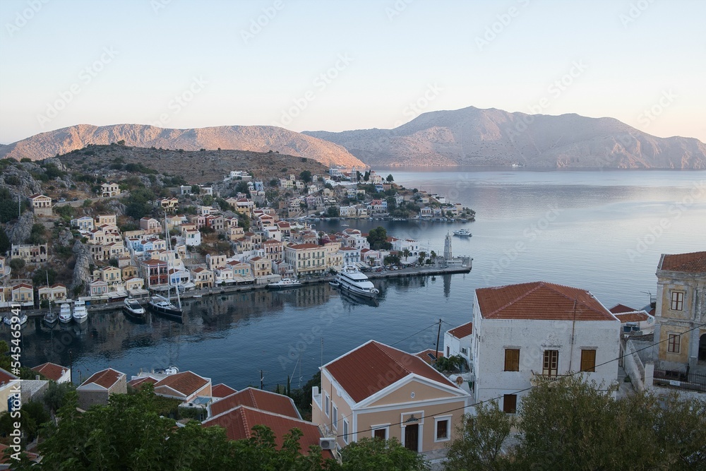 Beautiful view of the Symi Harbor on Symi Island, Greece with boats docked on calm waters at sunset