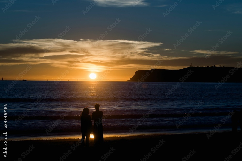 Silhouettes of women standing before the seascape enjoying the sunset