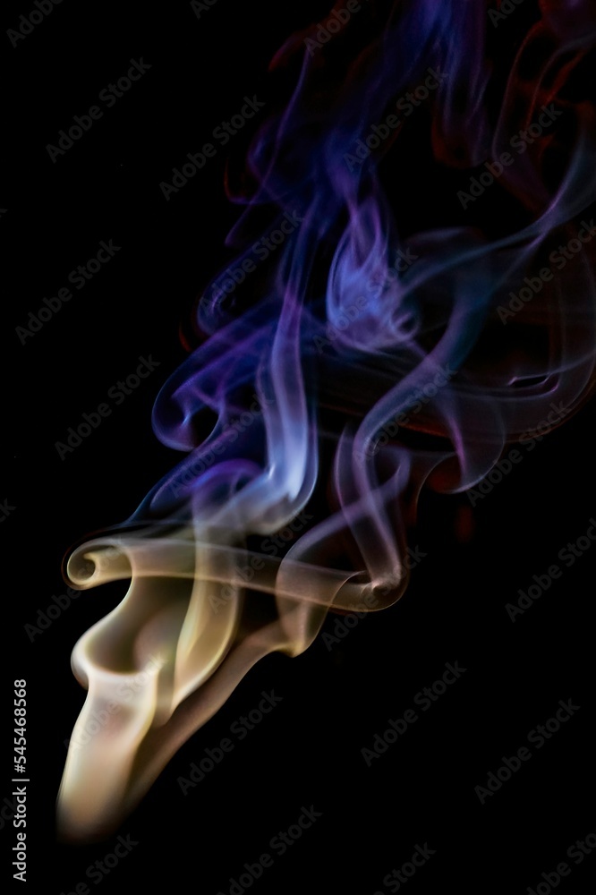 Beautiful shot of a colorful cone incense smoke trails isolated on black background