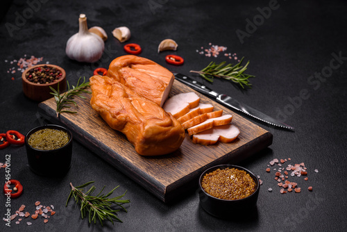 Tasty smoked fillet of chicken breast with spices and herbs on a wooden cutting board