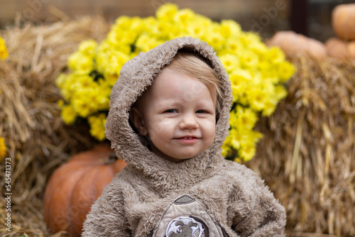 A small child on a background of pumpkins and hay