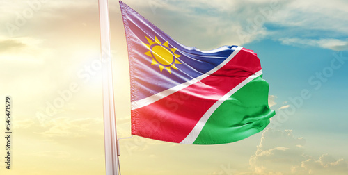 Waving Flag of Namibia in Blue Sky. The symbol of the state on wavy cotton fabric.