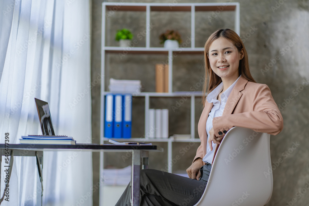 Beautiful Asian businesswoman working with laptop computer at office desk. Female entrepreneur typing financial documents. Check email at work. Financial accounting concept.