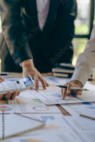 Young colleagues working together on startup projects in modern office Businessman brainstorming analyzing financial graphs calculating company earnings
 Vertical photo, flare