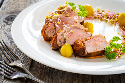 Fried pork loin with fresh vegetables on wooden table 