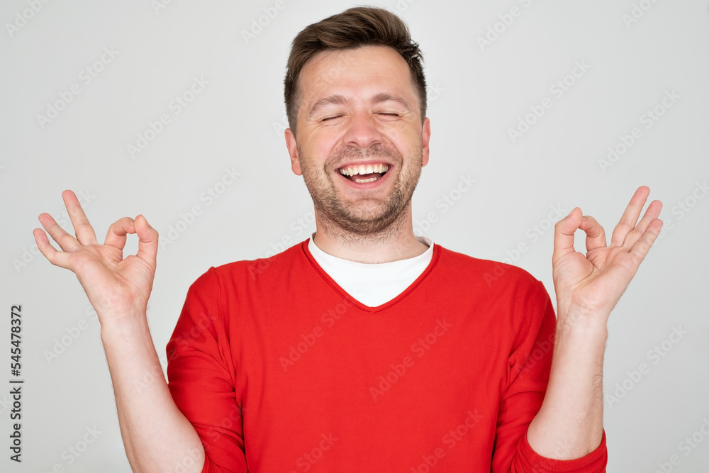 Mature man smiling with eyes closed doing meditation gesture with fingers Mature man smiling with eyes closed doing meditation gesture with fingers
