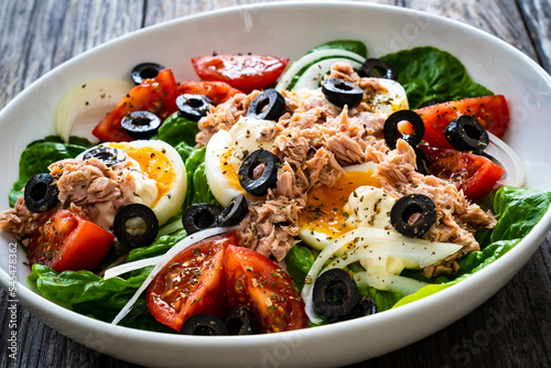 Nicoise salad - tuna, hard boiled eggs, greens, tomatoes and black olives photo