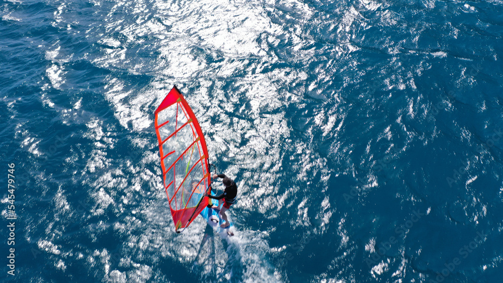 Aerial frone view photo of fit man practising wind surfing in Mediterranean bay with crystal clear deep blue sea