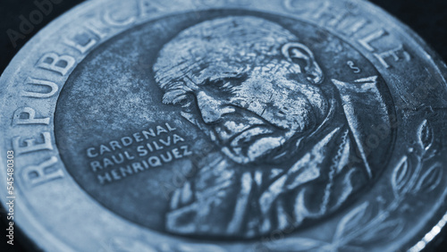 Coin of 500 Chilean pesos lies on a dark surface. Closeup. Peso of Chile. News about economy or money. Loan and credit. Interest and inflation. Blue tinted wallpaper or background. Macro