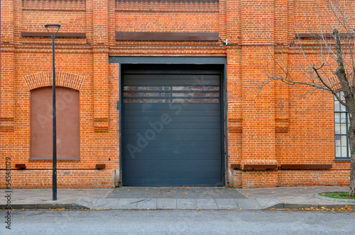 Red brick wall with automatic metal roller doors used in factory, warehouse, garage.