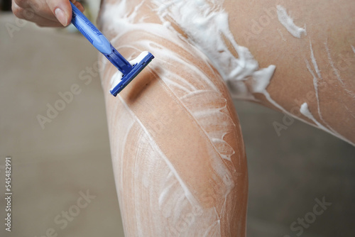 Shave with a razor. Shaving legs with a disposable razor in the shower. Removal of unwanted hair. Women's legs without epilation.
