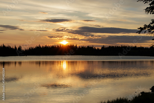 The sun rises over the water at an alpine lake in the Colorado Rockies