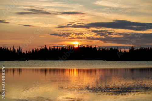 A beautiful orange sunrise over a lake in the mountains of Colorado with pine trees on the horizon