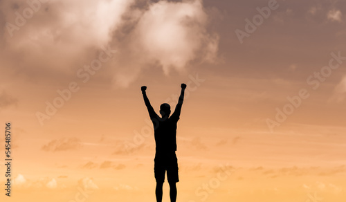 Silhouette of man with fist up to the sunset feeling strong and inspired 