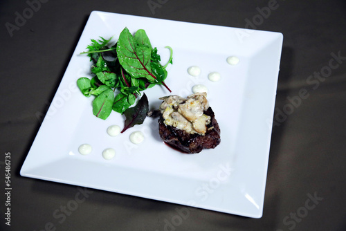 Cooked fillet mignon  with vegetables and sauce on a white plate