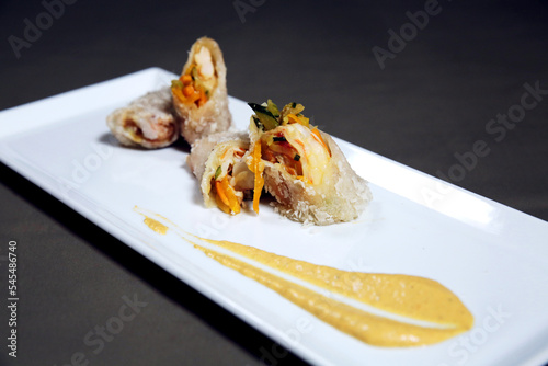 Spring rolls made of rice paper with shrimps, vegetables and sauce on a white plate. Fresh asian appetizer nems. Vietnamese Food
