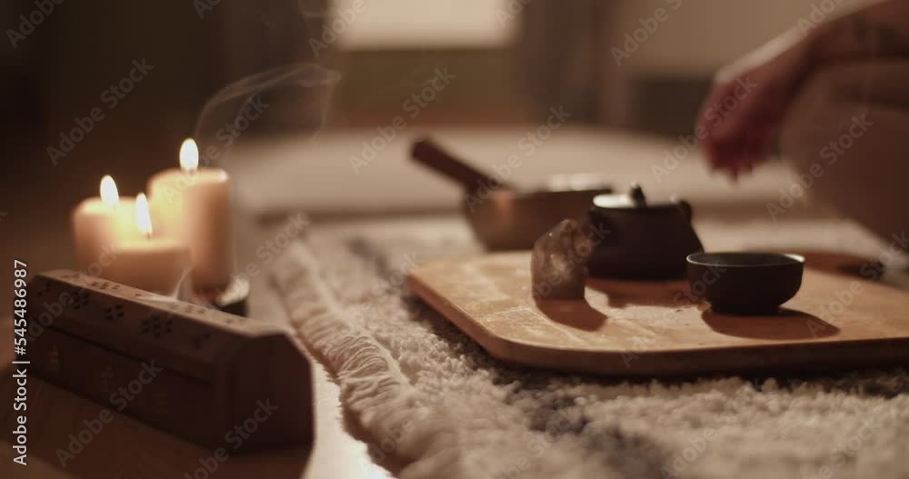 Incense and tea near meditating woman