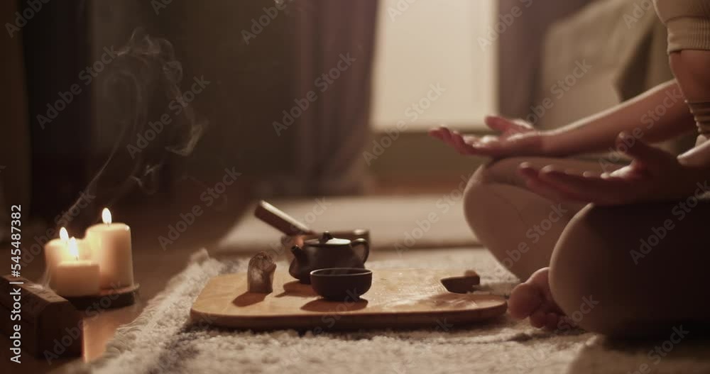 Female meditating near tea and incense