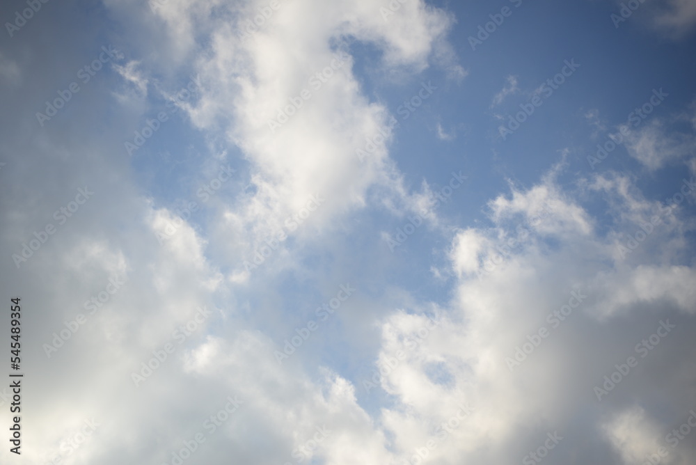 rays of the sun through cirrus clouds against a blue sky, white rainy clouds against a blue sky illuminated by the rays of the sun