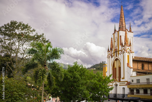 very tall neo-gothic church, white and gold, surrounded by tress