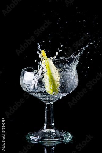 Slice of lemon making a splash in a glass of alcohol (ID: 545502989)