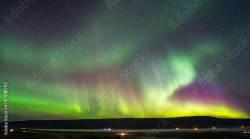 colorful northern light  Aurora  in the night sky with mountain  fog  horizon  road and small village