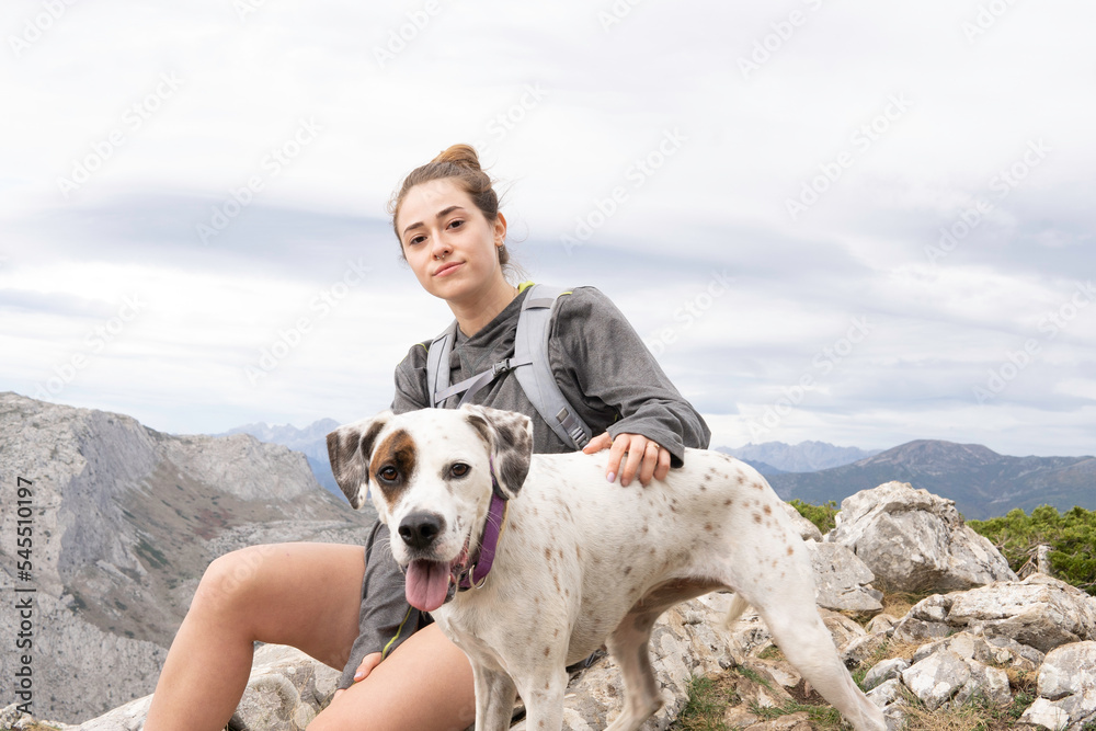 a young white girl dressed in mountain clothes and a gray backpack. Her dog accompanies her on this adventure. In the background you can see the mountain range. Wallpapers for hiking and climbing. a young white girl dressed in mountain clothes and a gray backpack. Her dog accompanies her on this adventure. In the background you can see the mountain range. Wallpapers for hiking and climbing.