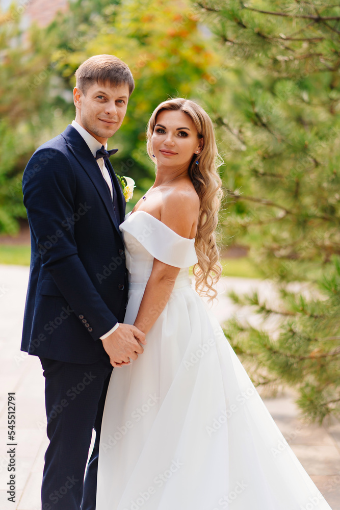 the groom and the bride in traditional wedding clothes in a park the groom and the bride in traditional wedding clothes in a park