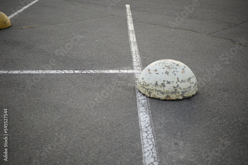 concrete traffic limiters, concrete tokens painted white, parking space, symmetrical lines on a concrete road, concrete hemispheres mounted on asphalt, concrete parking hemispheres, cones restricting  photo