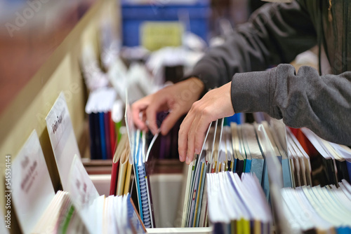 Selective focus of teen hands choosing music textbook at bookstore. 