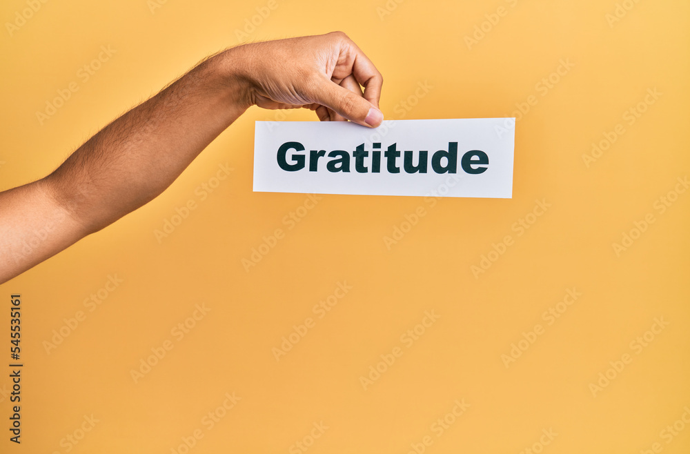 Hand of caucasian man holding paper with gratitude word over isolated white background Hand of caucasian man holding paper with gratitude word over isolated white background