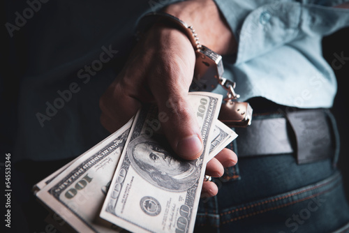 Fototapeta hand in handcuffs holding money