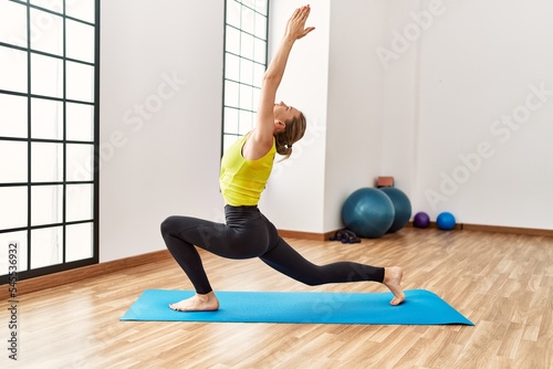 Young blonde girl training yoga at sport center.