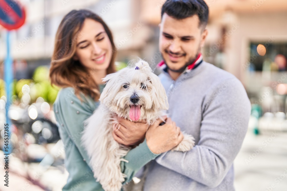 Man and woman holding dog standing together at street Man and woman holding dog standing together at street