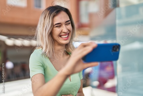 Young woman smiling confident watching video on smartphone at street