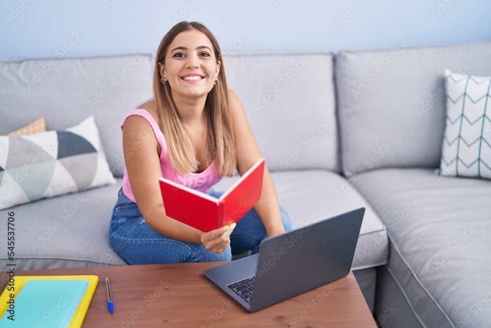 Young beautiful hispanic woman student sitting on sofa reading book at home Young beautiful hispanic woman student sitting on sofa reading book at home