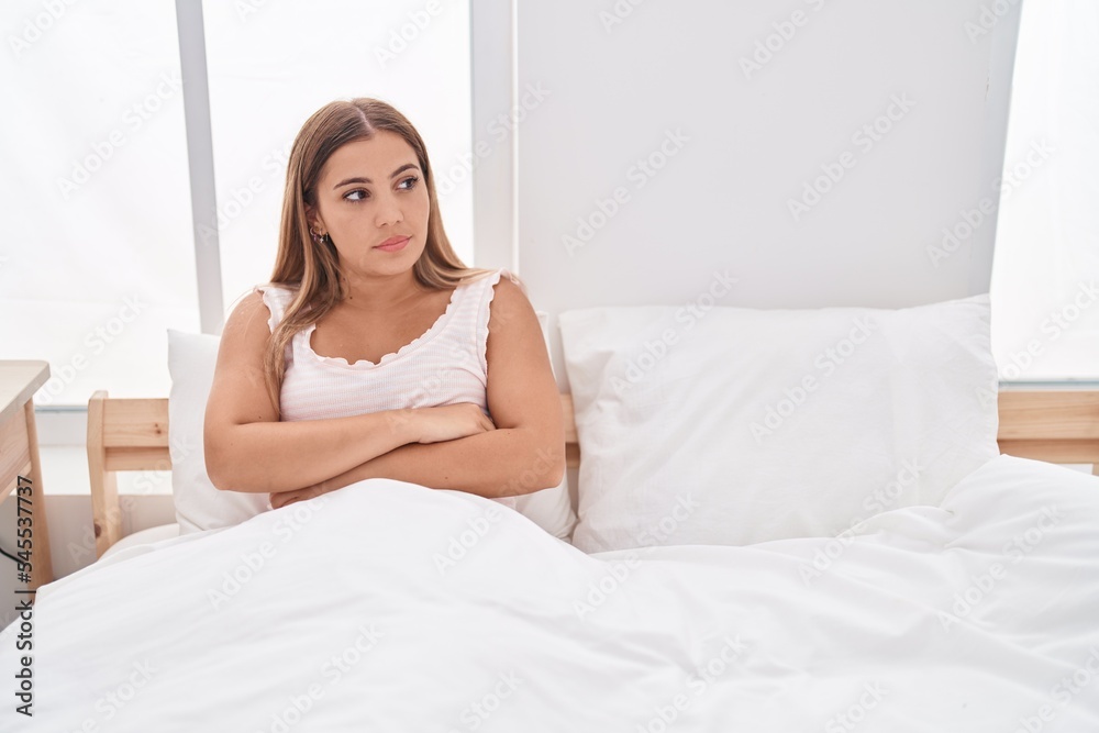 Young beautiful hispanic woman sitting on bed with unhappy expression and arms crossed gesture at bedroom Young beautiful hispanic woman sitting on bed with unhappy expression and arms crossed gesture at bedroom