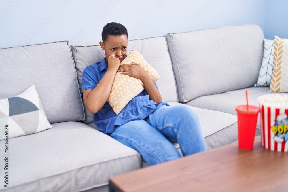 African american woman watching scare movie sitting on sofa at home African american woman watching scare movie sitting on sofa at home