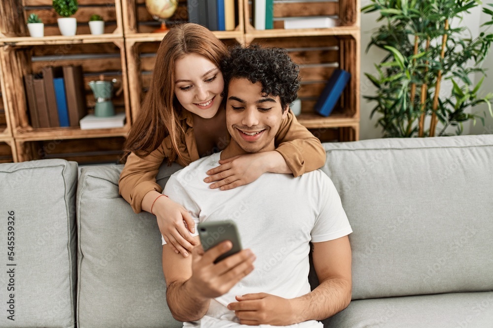 Young couple smiling happy and hugging sitting on the sofa at home. Young couple smiling happy and hugging sitting on the sofa at home.