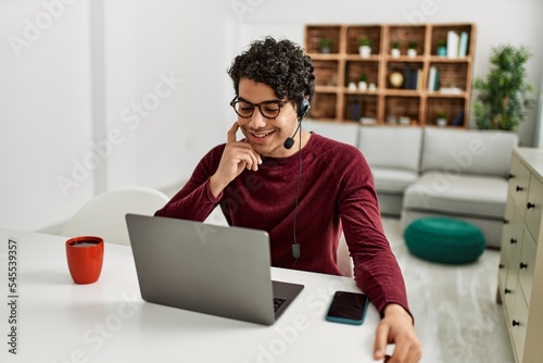 Young hispanic call center agent man working at home.