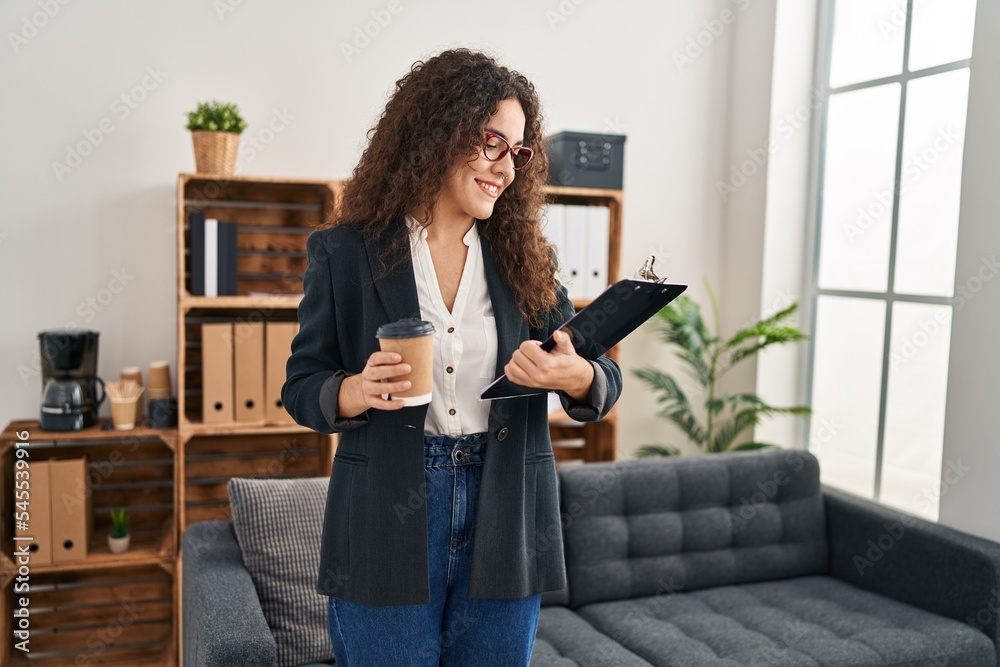 Young beautiful hispanic woman business worker drinking coffee reading document at office Young beautiful hispanic woman business worker drinking coffee reading document at office