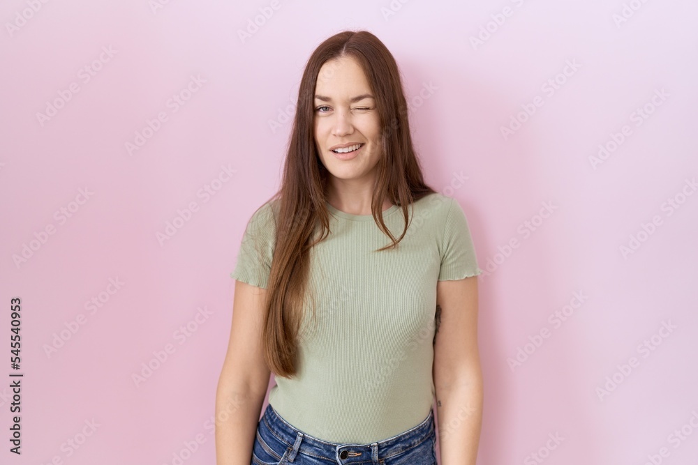 Beautiful brunette woman standing over pink background winking looking at the camera with sexy expression, cheerful and happy face. Beautiful brunette woman standing over pink background winking looking at the camera with sexy expression, cheerful and happy face.