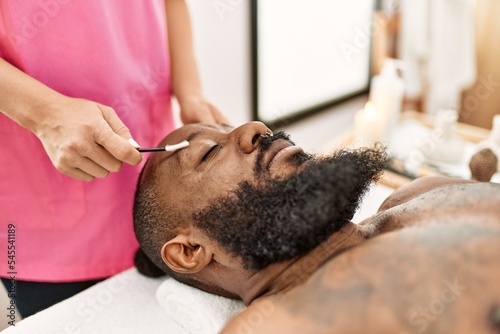 Young african american man having skin facial treatment at beauty center