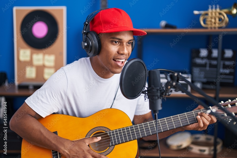 Obraz premium Young latin man musician singing song playing classical guitar at music studio